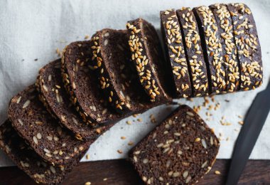 Keten peçetede siyah bir bıçağın yanında dilimlenmiş siyah ekmek.