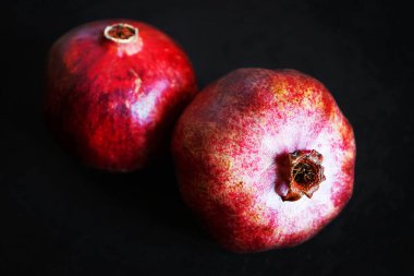 Koyu arkaplanda iki olgun nar.