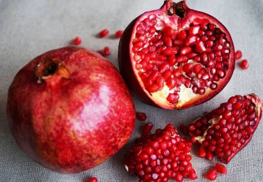 Gri arkaplandaki bütün bir narın yanında kesilmiş bir nar.