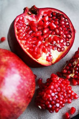 Gri arkaplandaki bütün bir narın yanında kesilmiş bir nar.