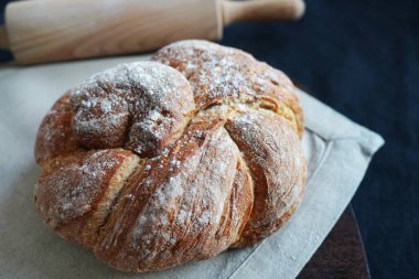 Koyu arkaplanda keten havlunun üzerinde taze ekmek.