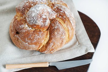 Tahtada taze ekmek ve beyaz arka planda bir bıçağın yanında keten masa örtüsü.