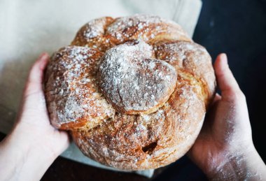 Çamaşır havlusunun arka planına ve siyah masa örtüsüne karşı kadın ellerinde taze ekmek.