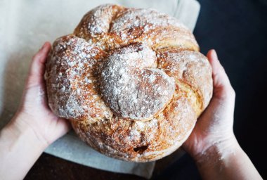 Çamaşır havlusunun arka planına ve siyah masa örtüsüne karşı kadın ellerinde taze ekmek.