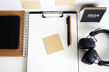 Not defterlerinin, takvimin, çıkartmaların, kalemlerin ve siyah kulaklıkların yanında kağıt olan klasör