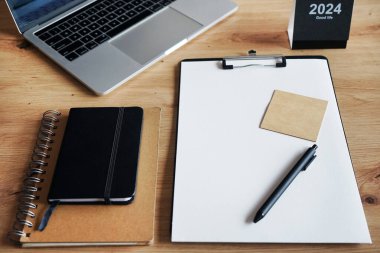 Klipsi, not defterleri, kalemleri, takvimi, dizüstü bilgisayarı ve kulaklığı olan işyeri