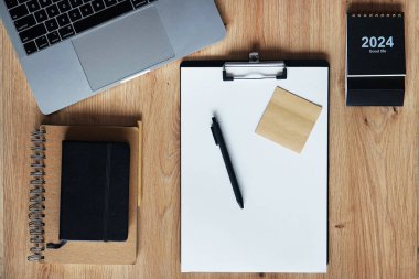 Klipsi, not defterleri, kalemleri, takvimi, dizüstü bilgisayarı ve kulaklığı olan işyeri