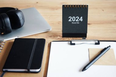 Klipsi, not defterleri, kalemleri, takvimi, dizüstü bilgisayarı ve kulaklığı olan işyeri