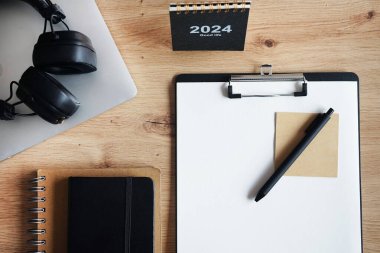 Klipsi, not defterleri, kalemleri, takvimi, dizüstü bilgisayarı ve kulaklığı olan işyeri