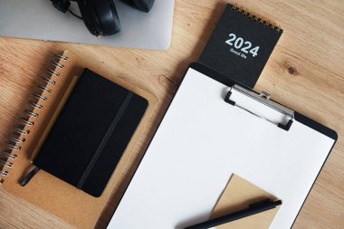 Klipsi, not defterleri, kalemleri, takvimi, dizüstü bilgisayarı ve kulaklığı olan işyeri