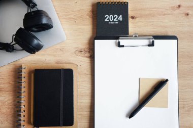 Klipsi, not defterleri, kalemleri, takvimi, dizüstü bilgisayarı ve kulaklığı olan işyeri