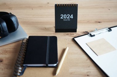 Klipsi, not defterleri, kalemleri, takvimi, dizüstü bilgisayarı ve kulaklığı olan işyeri