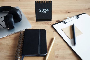 Klipsi, not defterleri, kalemleri, takvimi, dizüstü bilgisayarı ve kulaklığı olan işyeri