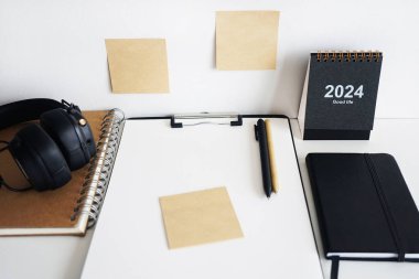 Not defterlerinin, takvimin, çıkartmaların, kalemlerin ve siyah kulaklıkların yanında kağıt olan klasör