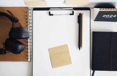 Not defterlerinin, takvimin, çıkartmaların, kalemlerin ve siyah kulaklıkların yanında kağıt olan klasör