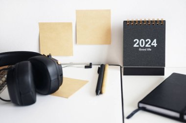 Not defterlerinin, takvimin, çıkartmaların, kalemlerin ve siyah kulaklıkların yanında kağıt olan klasör