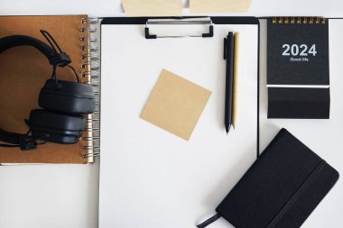 Not defterlerinin, takvimin, çıkartmaların, kalemlerin ve siyah kulaklıkların yanında kağıt olan klasör