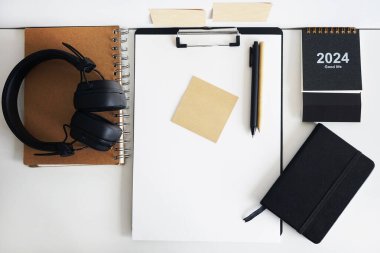 Not defterlerinin, takvimin, çıkartmaların, kalemlerin ve siyah kulaklıkların yanında kağıt olan klasör