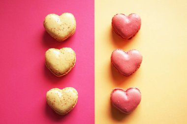 Pembe ve sarı arka planda kalp şeklinde makarnalar.