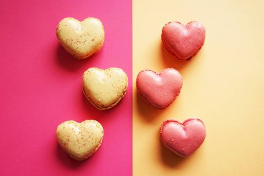 Pembe ve sarı arka planda kalp şeklinde makarnalar.