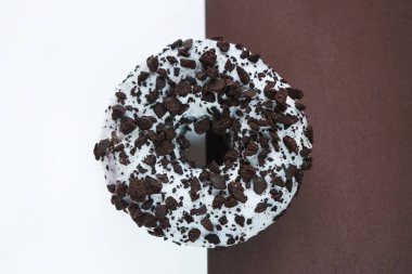 Beyaz jöleli çikolatalı çörek, beyaz ve kahverengi arka planda çikolata parçacıkları.