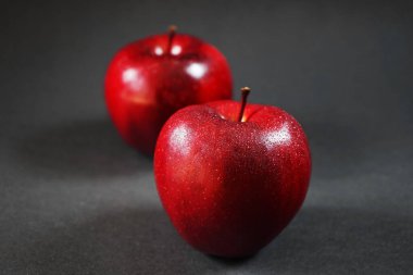 Olgun kırmızı elmalar koyu bir arka planda yakın çekim yaparlar.