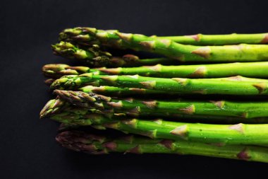 Koyu arka plan üzerinde taze yeşil kuşkonmaz