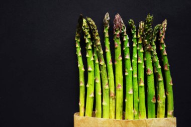 Koyu arka plan üzerinde taze yeşil kuşkonmaz