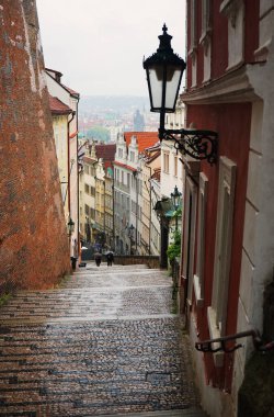 Prag 'ın eski yılının arka planında kasvetli yağmurlu bir günde Prag Kalesi' ne giden merdivenler