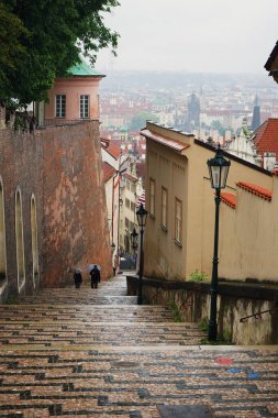 Prag 'ın eski yılının arka planında kasvetli yağmurlu bir günde Prag Kalesi' ne giden merdivenler