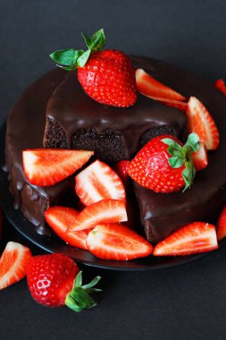 Çikolatalı pasta, kremalı ve koyu arkaplanda taze çilek.