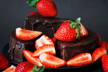 Çikolatalı pasta, kremalı ve koyu arkaplanda taze çilek.