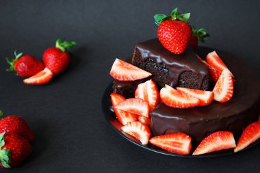 Çikolatalı pasta, kremalı ve koyu arkaplanda taze çilek.