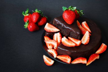 Çikolatalı pasta, kremalı ve koyu arkaplanda taze çilek.