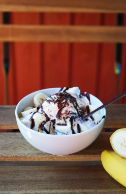 Muzlu dondurma, çikolata soslu ve beyaz tabakta dilimlenmiş muz.