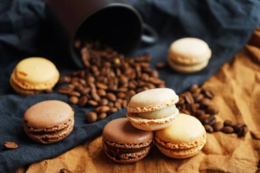 Siyah fincanın yanında kahve çekirdekleri ve koyu arkaplanda siyah ve kahverengi havlular.