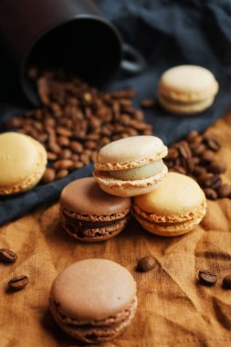 Siyah fincanın yanında kahve çekirdekleri ve koyu arkaplanda siyah ve kahverengi havlular.