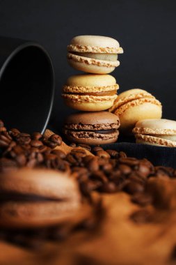 Siyah fincanın yanında kahve çekirdekleri ve koyu arkaplanda siyah ve kahverengi havlular.