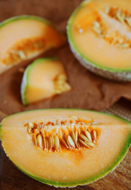 Olgun sarı kavun, tahta bir tahtada bir bıçak ve keten peçetenin yanında dilimlenmiş.