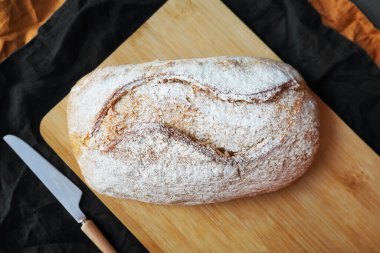 Tahtada tahıl ekmeği, keten peçetedeki bıçağın yanında.