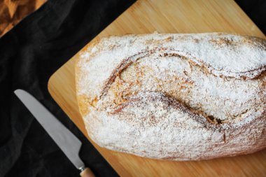 Tahtada tahıl ekmeği, keten peçetedeki bıçağın yanında.