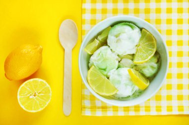 Limonlu dondurma, beyaz bir tabakta limon dilimleri ve sarı bir zemin üzerinde dilimlenmiş limonlar.