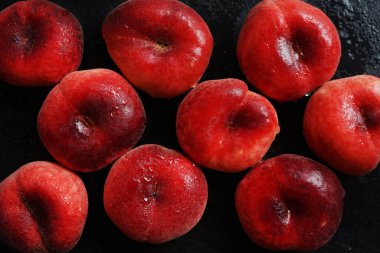 Olgun şeftaliler siyah bir tepside koyu bir zemin üzerinde