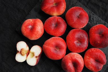 Olgun şeftaliler siyah bir tepside koyu bir zemin üzerinde