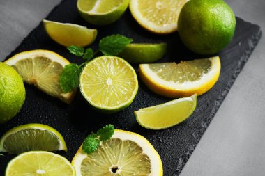 Nane şekerinin yanında dilimlenmiş limon ve limon gri arka planda siyah bir tepside.