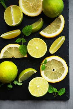 Nane şekerinin yanında dilimlenmiş limon ve limon gri arka planda siyah bir tepside.