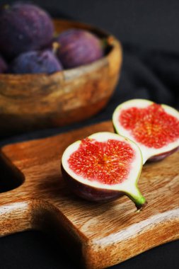 Olgunlaşmış ve incir dilimlenmiş. Tahtanın üzerinde, karanlık bir arka planda.
