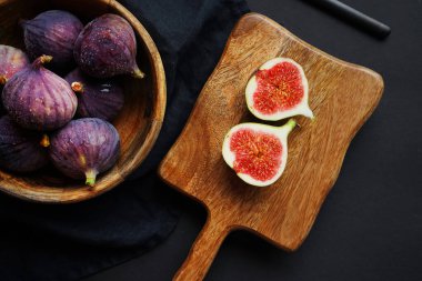 Olgunlaşmış ve incir dilimlenmiş. Tahtanın üzerinde, karanlık bir arka planda.
