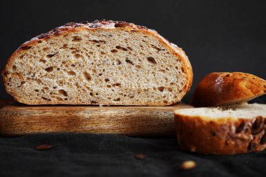 Koyu bir arka planda tahtadan parçalar kesmek için taze tahıl ekmeği.