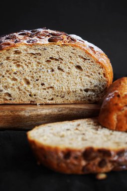 Koyu bir arka planda tahtadan parçalar kesmek için taze tahıl ekmeği.